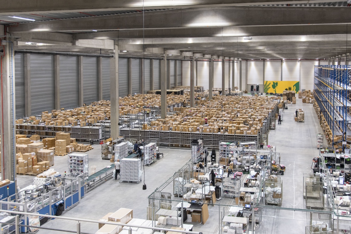 Massive order fulfilment center showing the full floor of goods and workers...