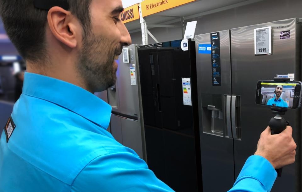 Mitarbeiter filmt Kühlschrank mit Smartphone