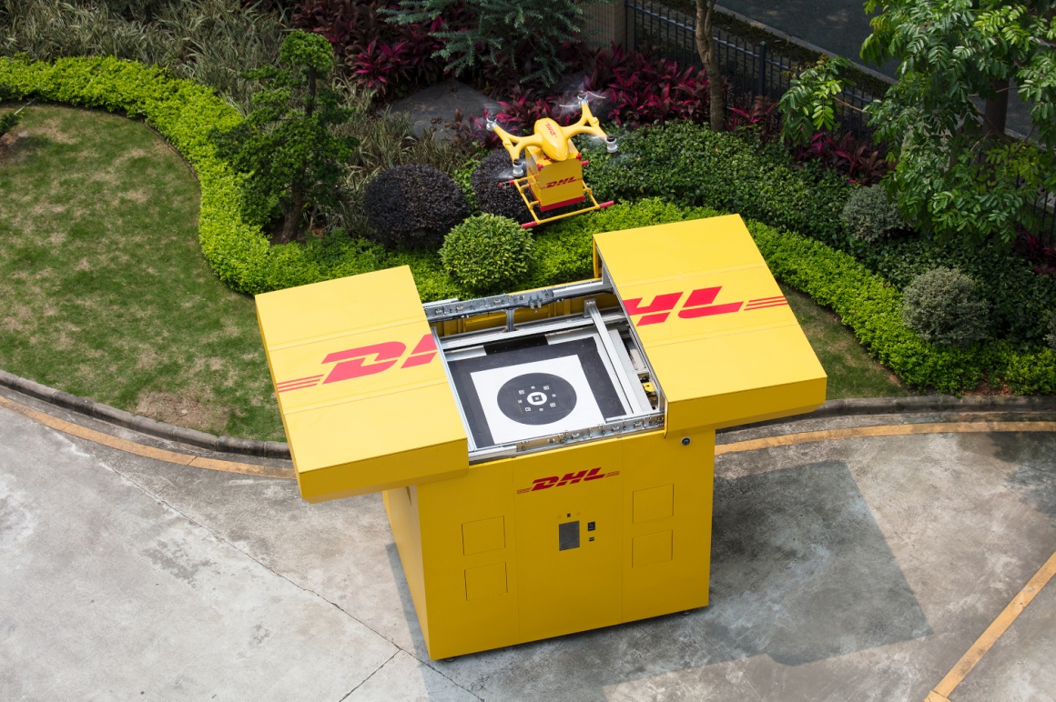 Eine gelbe DHL-Drohne landet auf einer gelben DHL-Station, die sich oben...