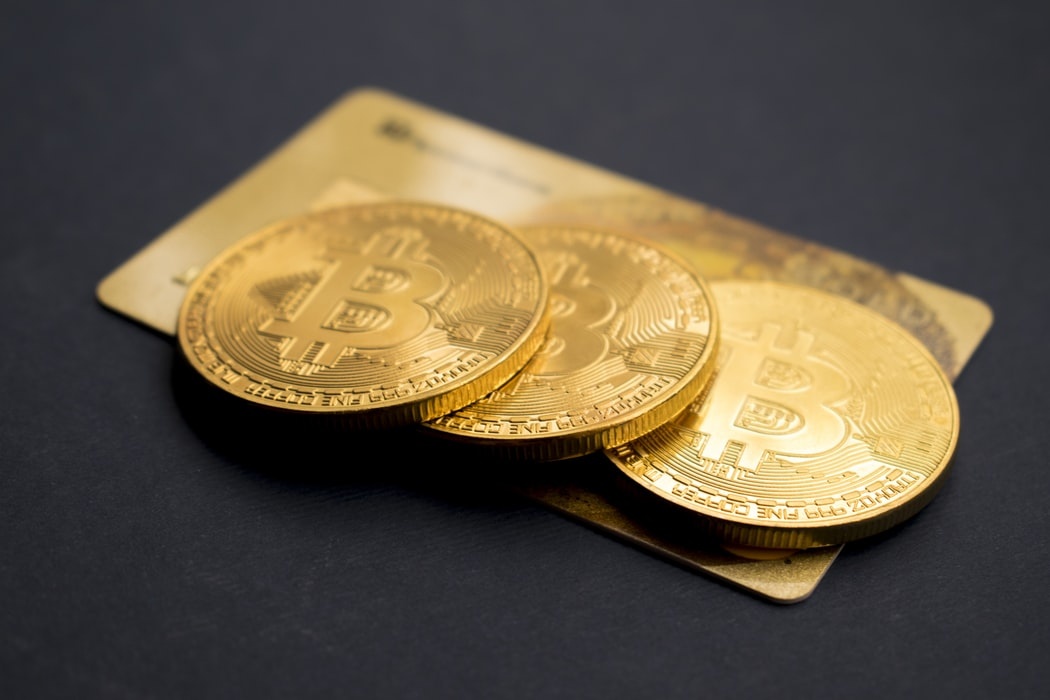 Drei goldene Münzen liegen auf einer Kreditkarte